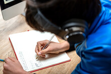 UK, Boy In Headphones Writing In Notebook
