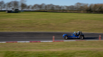 Wall Mural - A panning shot of a racing car as it circuits a track.