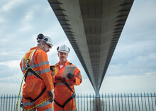 UK, East Yorkshire, Two Engineers Looking At Tablet Under Bridge