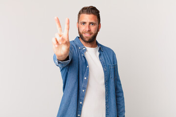 young handsome man smiling and looking friendly, showing number two