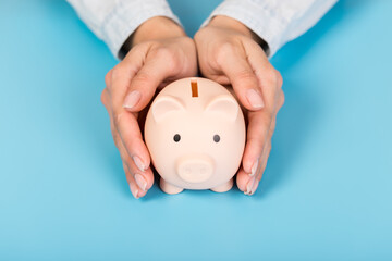 Wall Mural - Piggy bank in hand on blue background, space for text. Finance, saving money. Business to success and saving for retirement concept