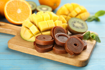 Composition with delicious fruit leather rolls on light blue wooden table