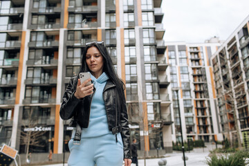 Wall Mural - Young beautiful brunette girl on the street makes a selfie on the phone