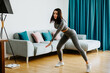 © shevtsovy - Athletic woman goes in for sports at home, training online. Home workout. Slim female stretching at home and weight loss workout in a living room.