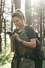 Female hiker is using smartphone for navigation in green forest