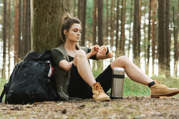 Female hiker during small halt sitting in green forest