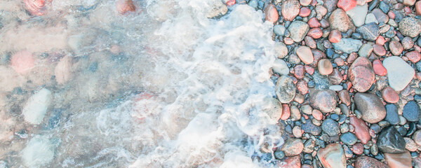 sea foam on wet pebbles on the beach on a sunny day, close up