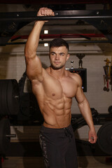 Wall Mural - Attractive tall muscular bodybuilder doing heavy deadlifts in modern fitness center.