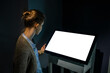 © zyabich - White screen, mock up, future, copyspace, template, technology concept. Woman looking at blank interactive touchscreen white display of electronic kiosk at futuristic exhibition or museum