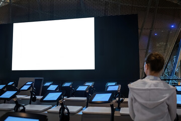 White screen, scifi, technology, futuristic, template, mock up, entertainment concept. Woman looking at large wall blank interactive white display at science exhibition, museum or cinema