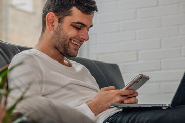 young man at home with mobile phone and computer