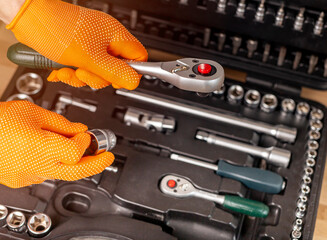 Wall Mural - Male hand in building glove with socket ratchet handle taking from repair suitcase. Industrial metal tool, close up.