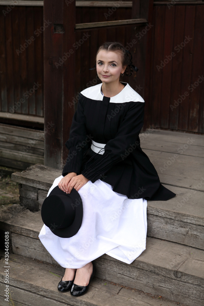 Amish fashion style. Fashion girl wearing stylish black and white dress and  hat at countryside. Portrait of pretty woman in village. Stylish amish  look. Amish dress. Lifestyle Stock-bilde | Adobe Stock
