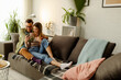 Happy couple relax on couch in living room watch movie on smartphone together.