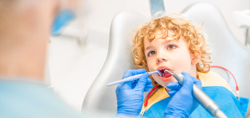 Wall Mural - Pretty little boy in dental office, having his teeth checked by female dentist .