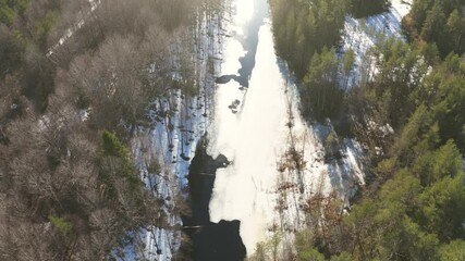 Wall Mural - Frozen river in sunny spring day, aerial flight on drone above Karelian nature landscape.