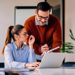 Businessman discussing with female colleague and writing notes in note pad