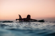 Portrait From The Water Of Surfer Girl With Beautiful Body On Surfboard In The Ocean At Sunset Time In Bali