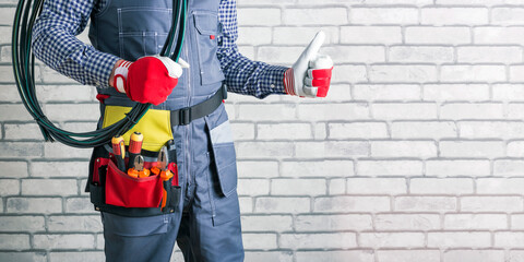 Wall Mural - Electrician with wires and electric tools near brick wall, space for text. Banner.