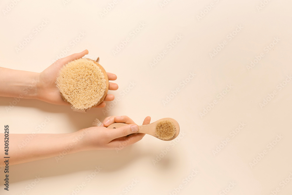 Female hands with massage brushes on color background