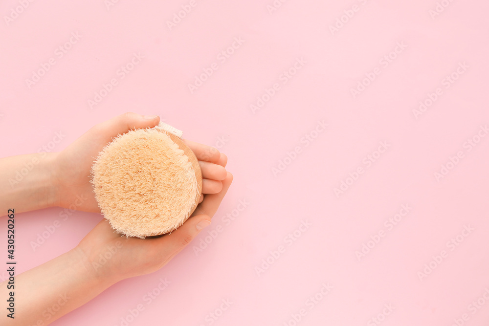 Female hands with massage brush on color background