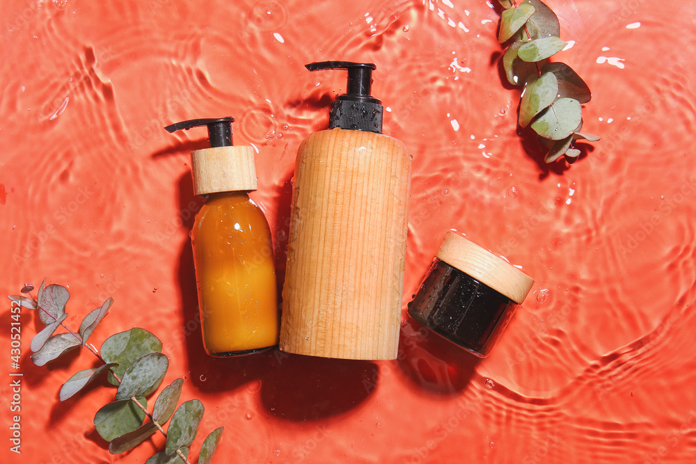 Cosmetic products and eucalyptus branches in water on color background