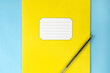 © Ольга Мылица - a yellow school notebook with a pen lies on a blue background. Pattern