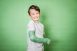 © epiximages - cool young schoolboy with broken arm and green plaster posing in front of green background in the studio