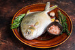 Fresh Raw Florida Pompano fish on a  rustic plate. Dark background. Top view