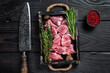 Raw Diced pork cubs meat with spices in a rustic tray. Black wooden background. Top view