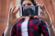 © GalakticDreamer - Blurred female tourist using modern mobile technology for clicking selfie images during travel sightseeing, millennial woman holding cellphone device with selective focus on touchscreen with photo