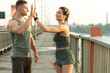 © blackday - Athletic couple making high five gesture during fitness workout on city street
