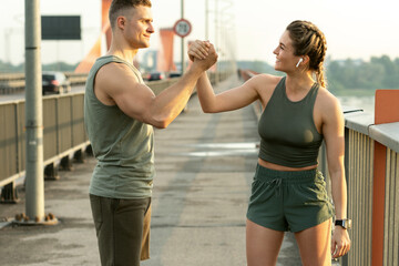 Wall Mural - Athletic couple making handshake during fitness workout on city street