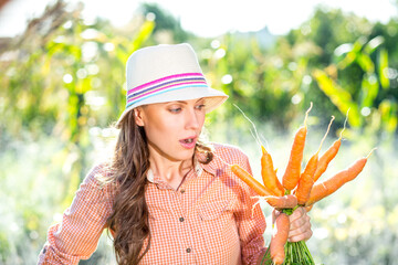 Wall Mural - Beautiful farmer woman with carrots, outdoor shot