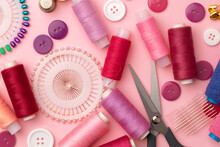 Sewing Accessories Including Thread Spools And Pins On Pink Background