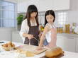 © Bangkok Click Studio - A cute and beautiful mother tie apron for her young and little daughter during she teaches her how-to cooking. Idea for love and relationship