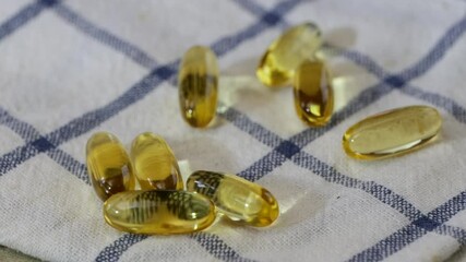 Poster - Fish oil, or Omega 3 Oil capsules falling onto a napkin in super slow motion