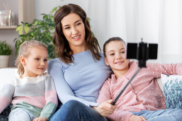 Wall Mural - family, technology and people concept - happy mother and daughter with smartphone taking selfie at home