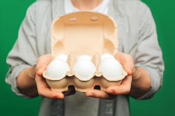 Close up young man holds eggs, isolated on green background