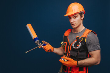 Curious builder is having equipment in arm, isolated over blue background