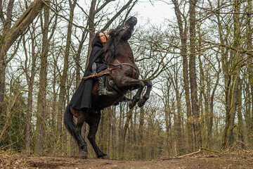 Wall Mural - beautiful woman riding in historical costume as a warrior horse digs hooves in the air