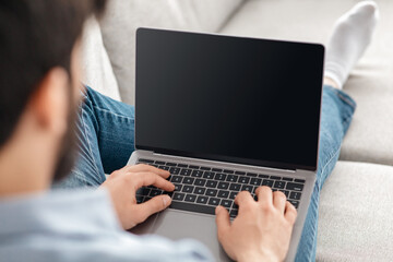 Technology concept. Unrecognizable guy using laptop computer with blank screen, mockup, selective focus