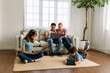 © twinsterphoto - Young caucasian family with father, mother, daughter and son using laptop, digital tablet and mobile phone to browse social media in living room at home