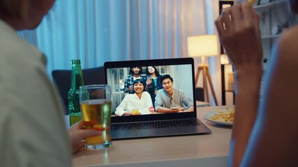 Wall Mural - Young Asia female drinking beer having fun happy moment night party event online celebration via video call in living room at house at night. Social distancing, quarantine for coronavirus prevention.