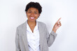 © Roquillo - African American businesswoman with curly bushy hair wears  formal clothes over white background looking at camera indicating finger empty space sales