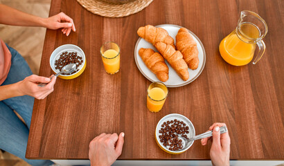 Family couple breakfast top view. Snack with dry breakfast, juice and croissants of a mature couple and a pleasant time in the kitchen.