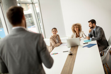 Group of young business people working and communicating while sitting at the office desk together