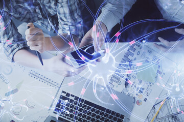 Double exposure of neuron drawing and man and woman working together holding and using a mobile device. Education concept