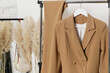 Corner in fashion atelier with fashionable tailored blazer hanging on a rack. Modern premium quality hand made woman's fashion.