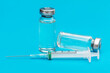 © igorkol_ter - Two vaccine vials and syringe on blue background. COVID-19 vaccination.